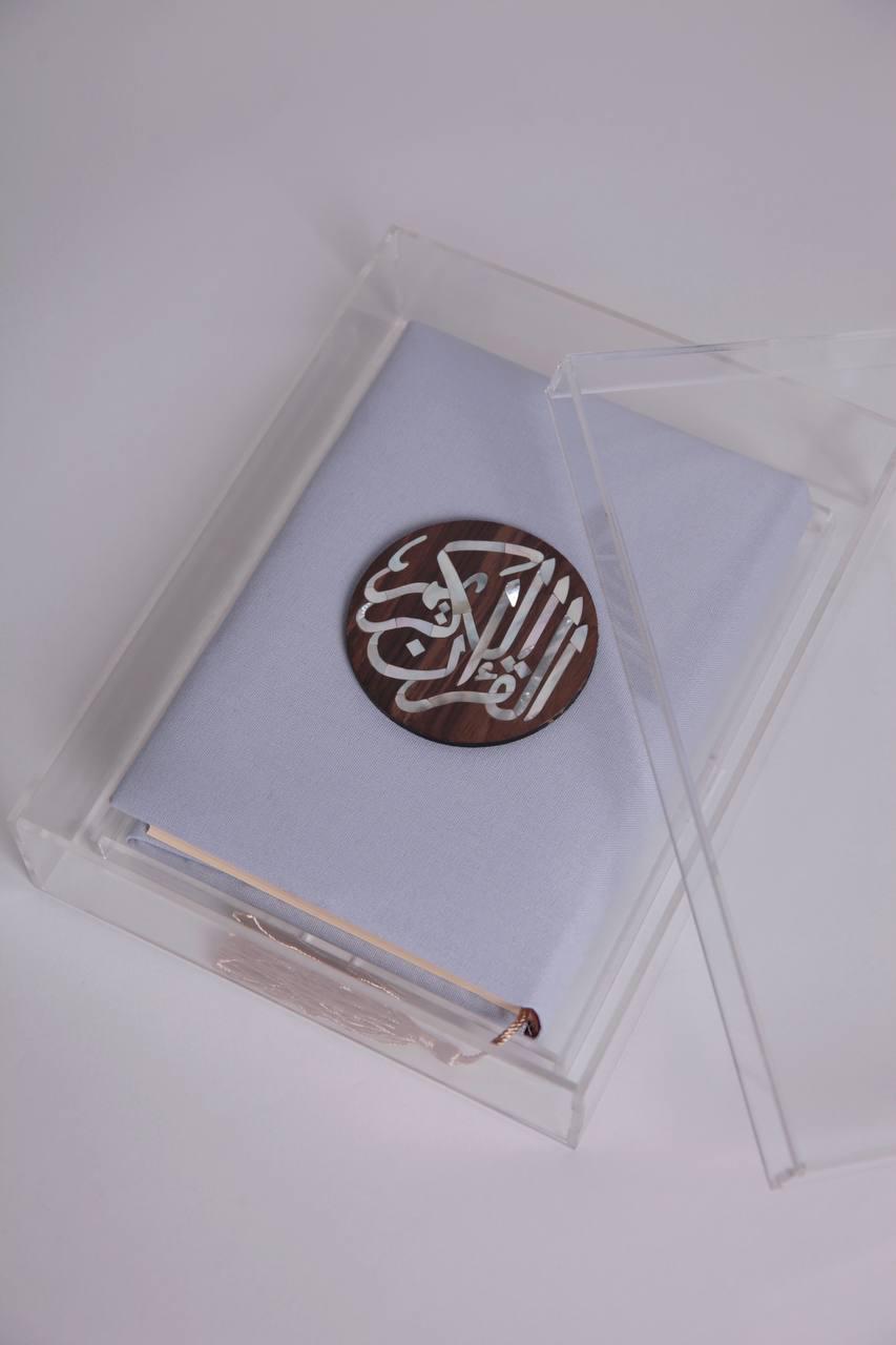 قرآن صغير أزرق اللون مع مصدفة خشبية مستديرة